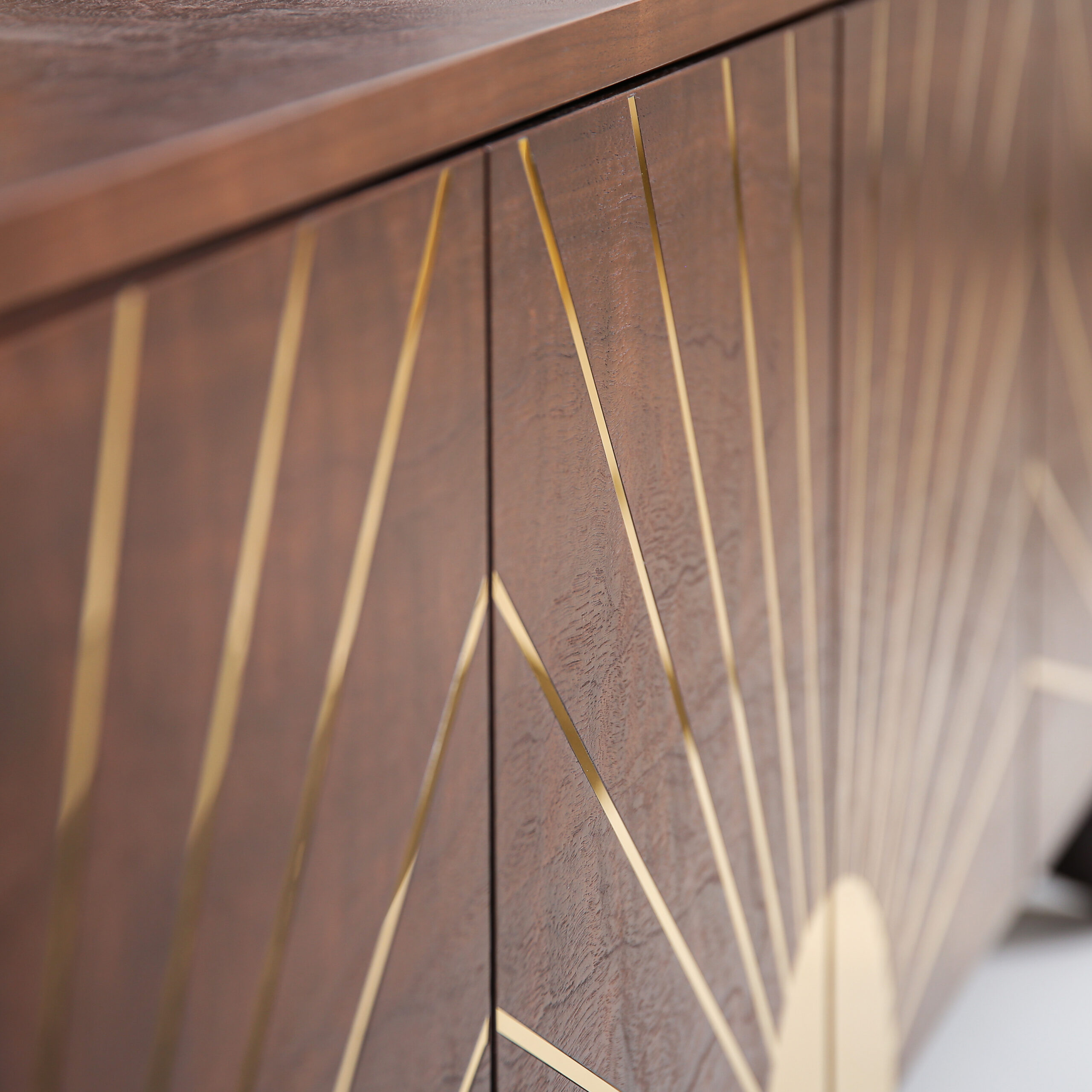 Polished brass inlay detail on the Astor Sideboard highlighting architectural geometry.