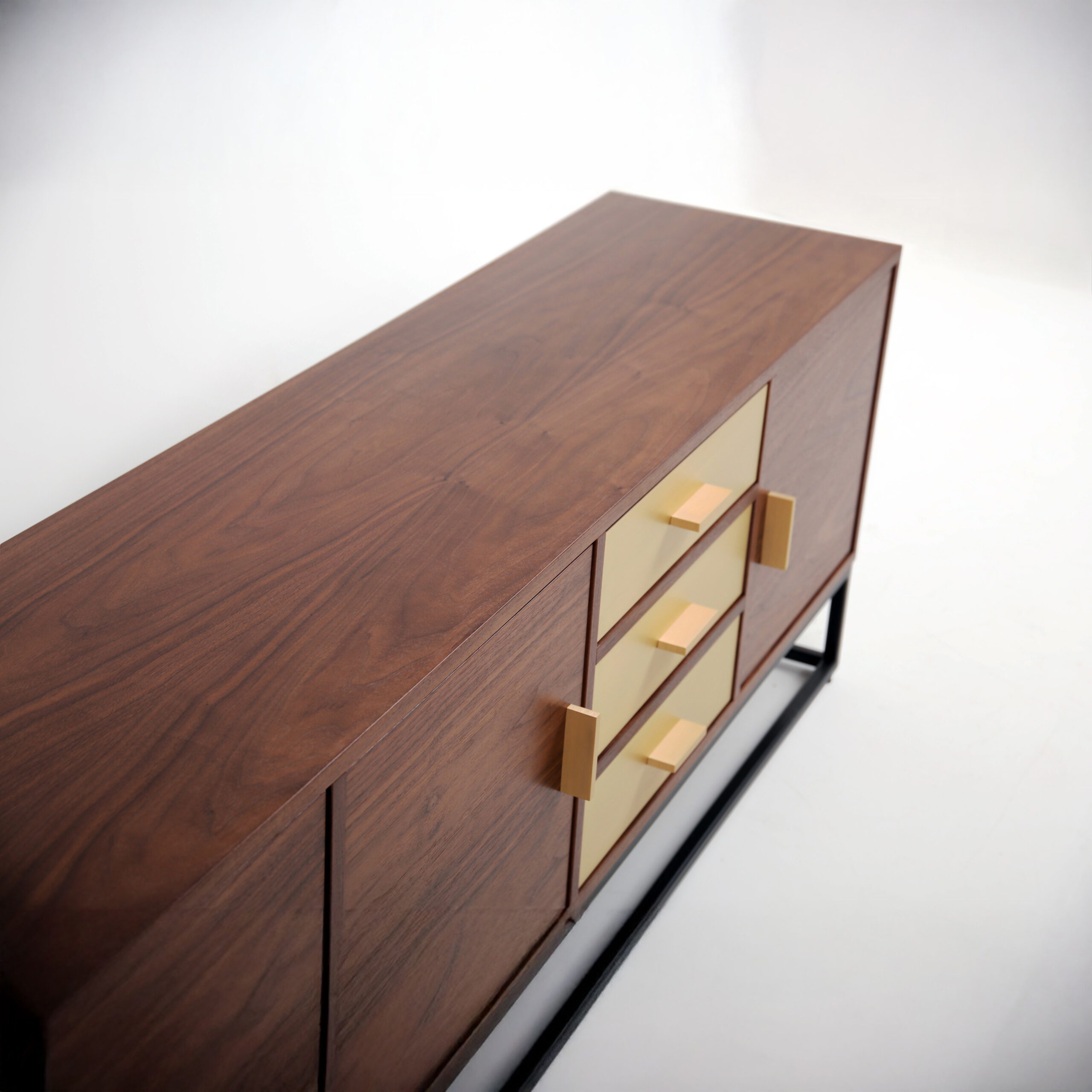 Close-up of Kópavogur Sideboard showing brushed brass drawer fronts and warm walnut grain.